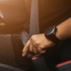 Picture of individual fastening their seatbelt in a car.